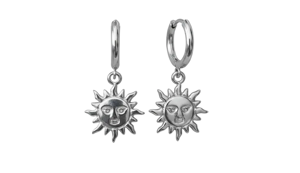 Pair of silver sun-shaped earrings with face designs on a white background