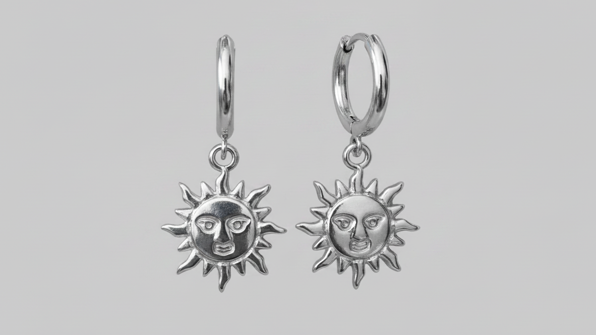 Silver sun-shaped earrings with face design on a gray background