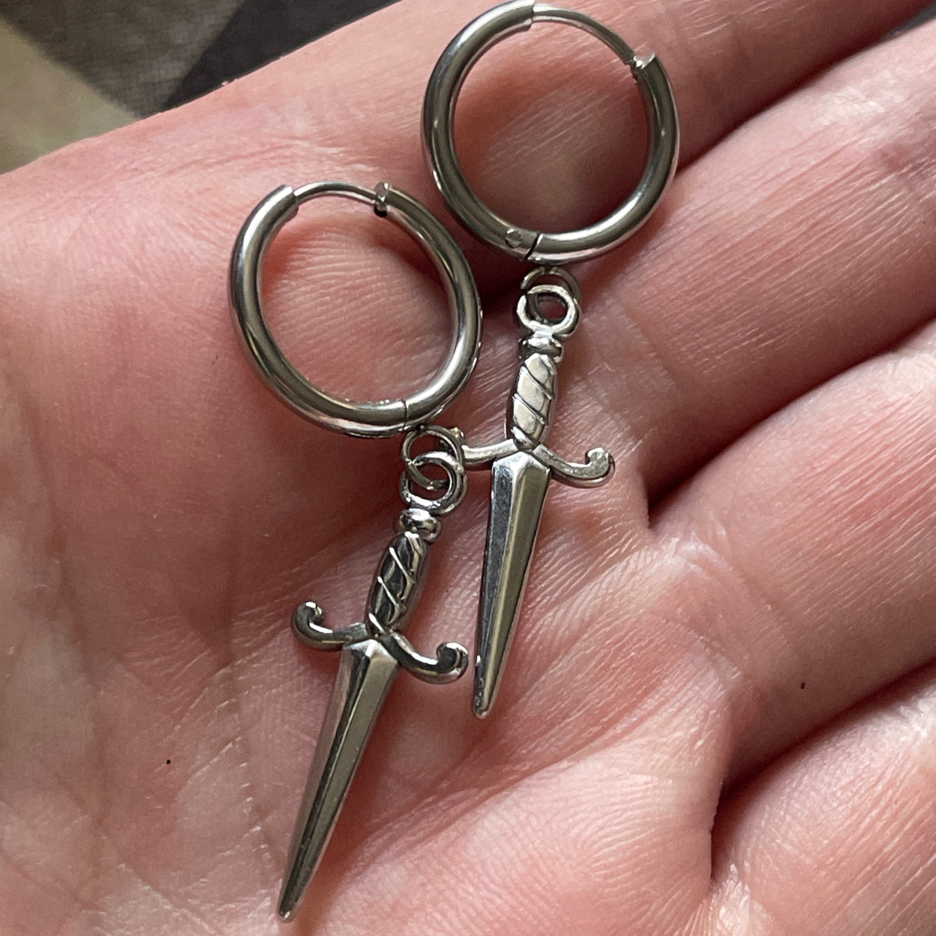 Silver keychain with dagger charm held in a hand