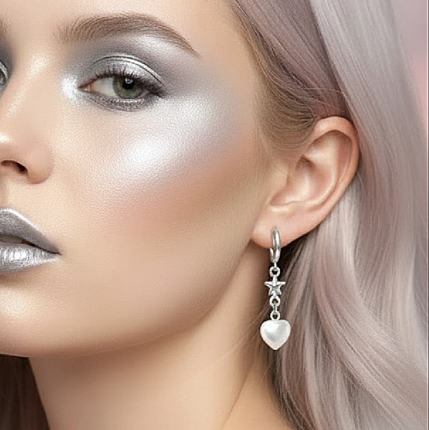Close-up of a woman's face with silver makeup and a heart-shaped earring.