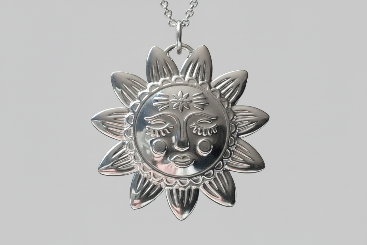 Silver sun-shaped pendant with face design on a gray background