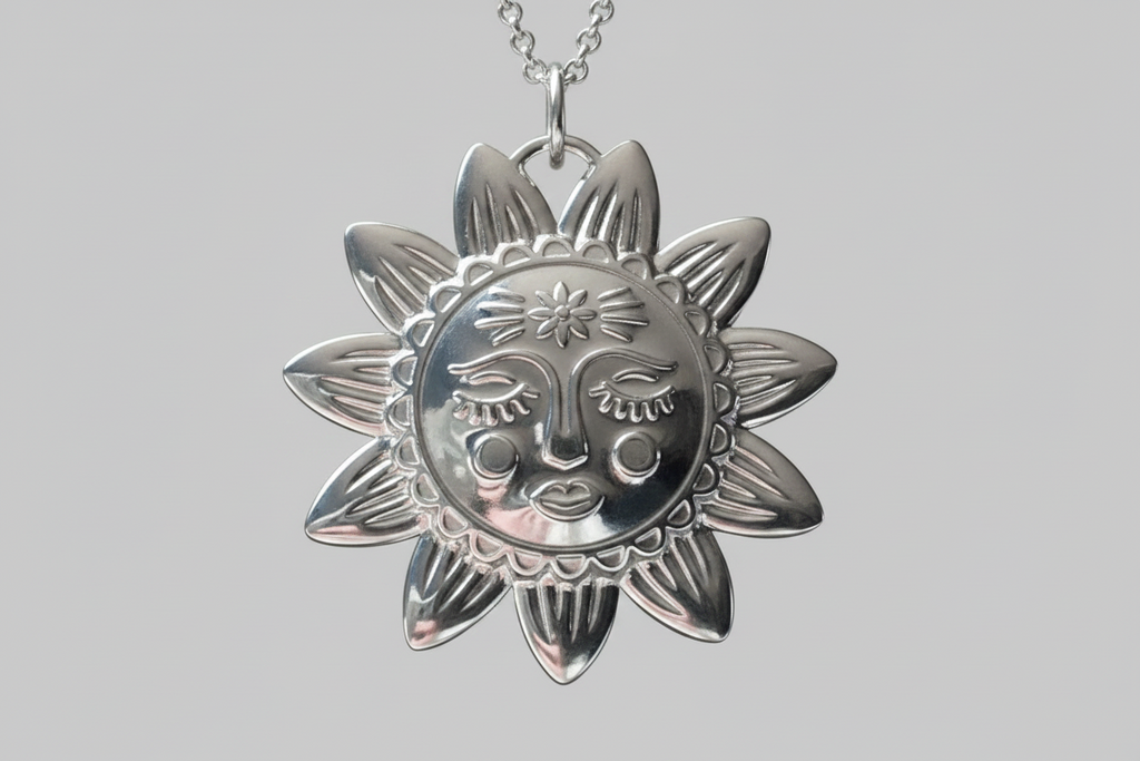Silver sun-shaped pendant with face design on a gray background