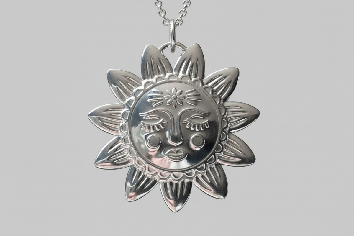Silver sun-shaped pendant with face design on a gray background