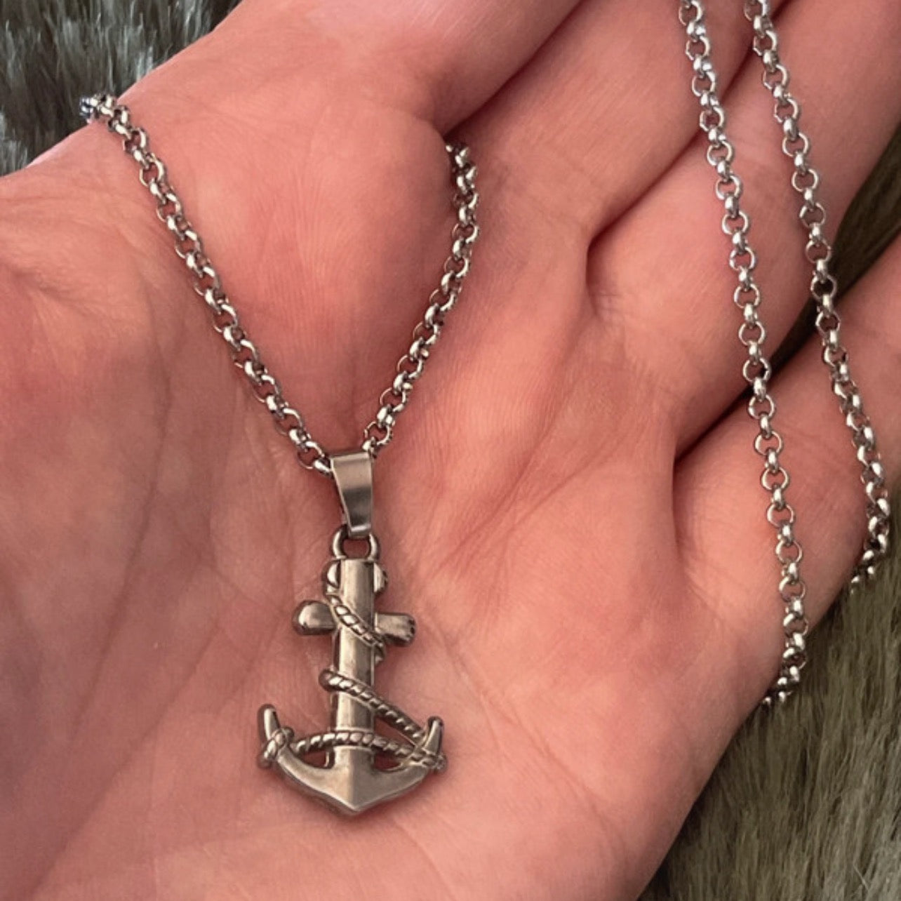 Silver anchor necklace on a hand