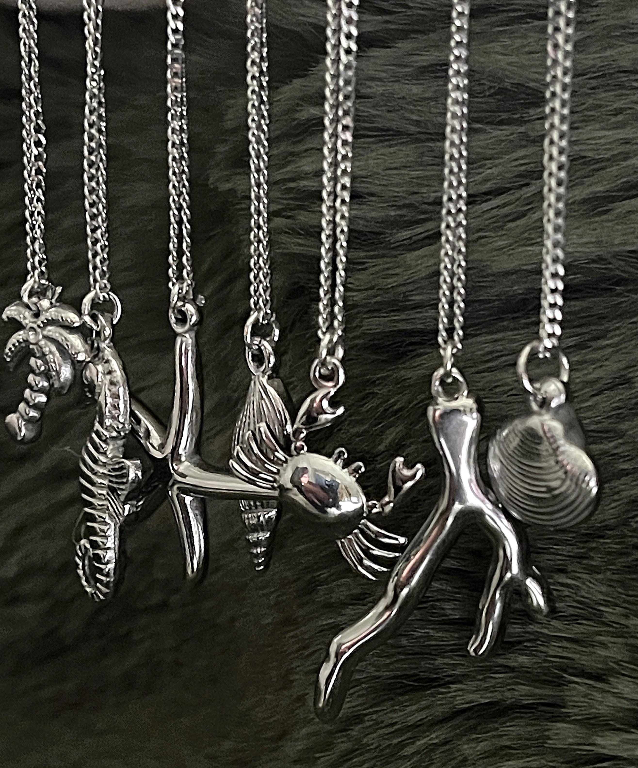 Collection of silver necklaces with various pendants on a dark fur background