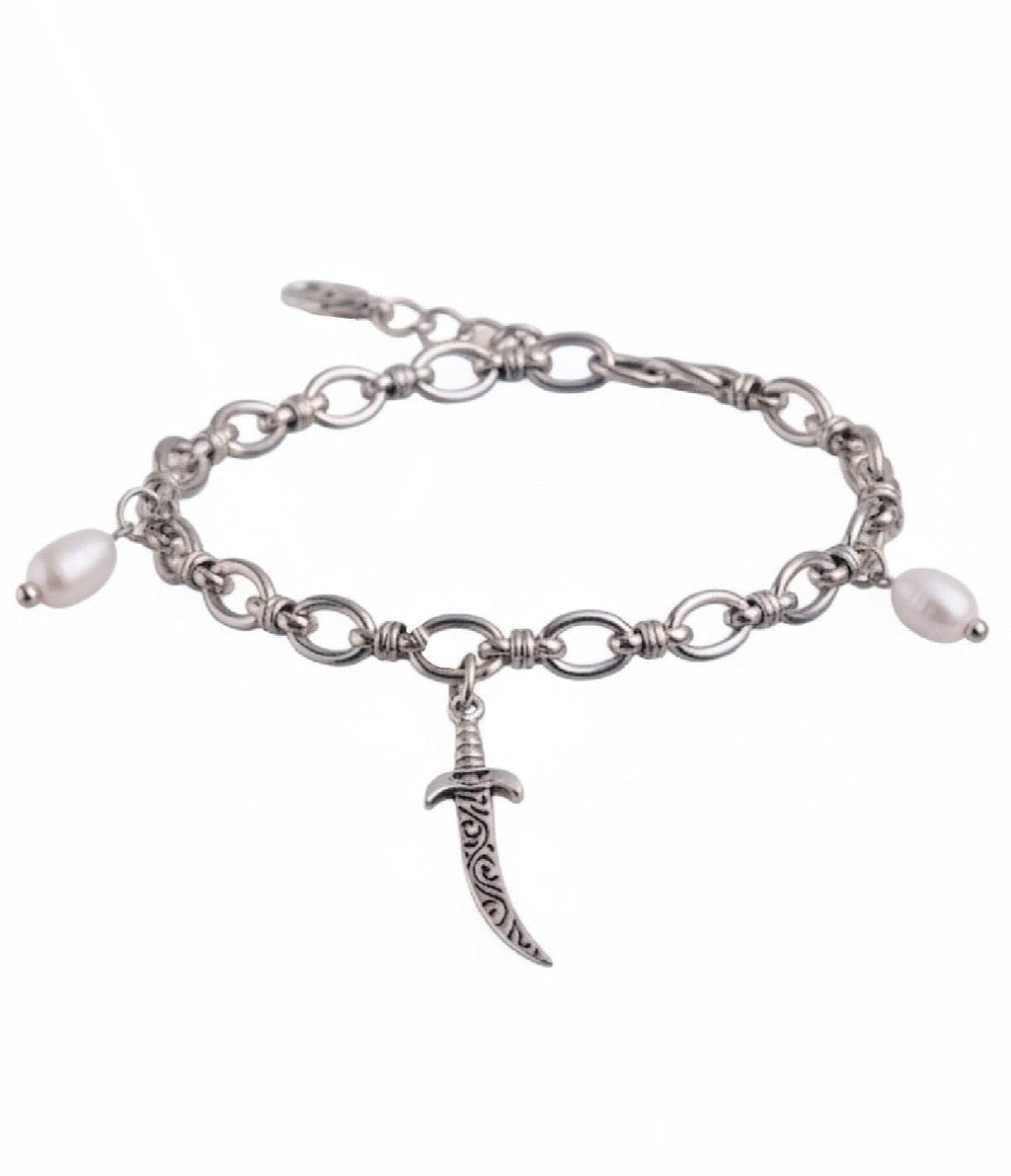 A silver-tone chain bracelet featuring a dangling ornate dagger charm and two small white pearl beads on either side, shown against a plain white background.