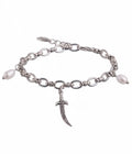 A silver-tone chain bracelet featuring a dangling ornate dagger charm and two small white pearl beads on either side, shown against a plain white background.