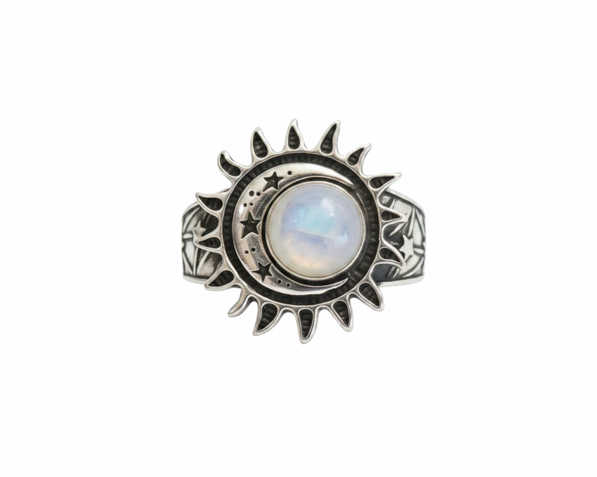 A silver sun and moon ring featuring a central round moonstone with a soft blue and white iridescent sheen, set against a plain white background.