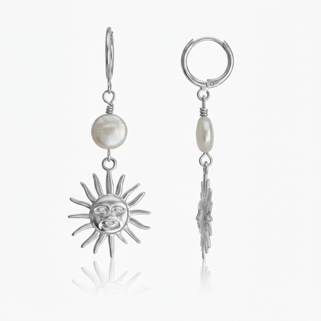 A pair of silver drop earrings featuring a sun face charm, a white freshwater pearl, and a small silver sun charm, shown on a clean white background.