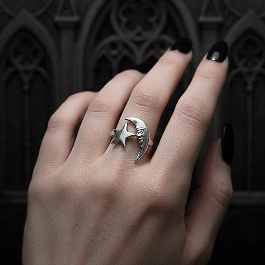 Silver ring with star and moon design on a hand against a dark background