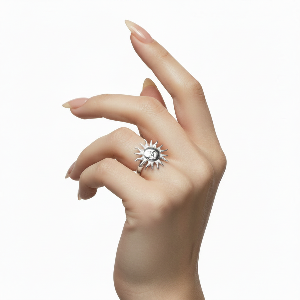 Hand wearing a silver ring with a sun design on a white background