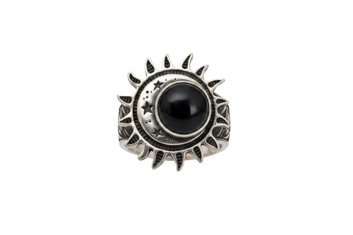 A silver ring featuring a central black round stone surrounded by a sunburst and crescent moon design, set against a plain white background.