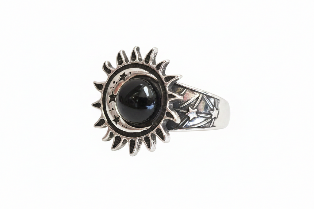 A silver ring featuring a sunburst and moon design with a central black round stone and star details on the band, shown against a plain white background.