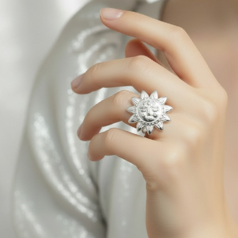 Silver sun-shaped ring on a hand with a soft background