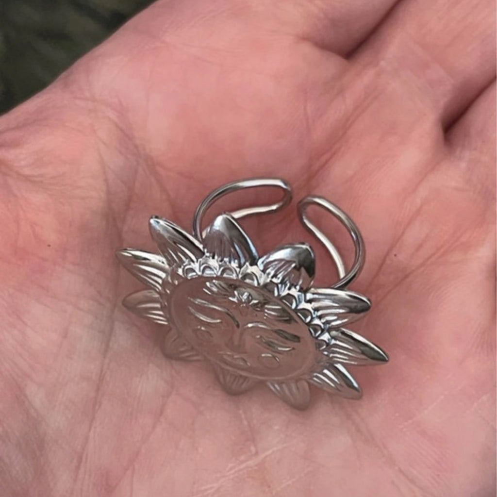 Silver sun-shaped ring on a hand
