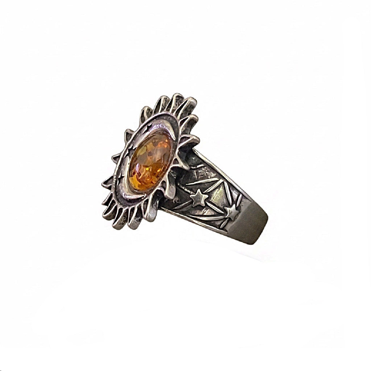 A side view of a silver ring with sun, moon and star detail with a round amber gemstone on a white background.