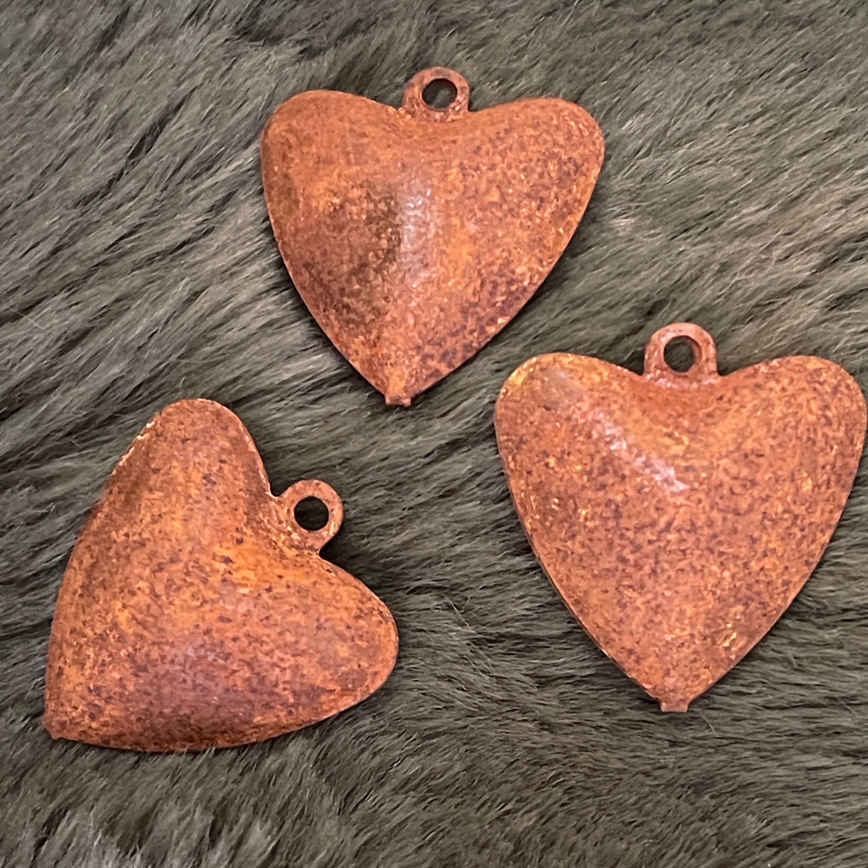Three rusted heart-shaped metal bells on a fur surface