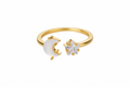 A toned gold open ring featuring a crescent moon moonstone and a small clear zircon star on the other side, shown on a plain white background.