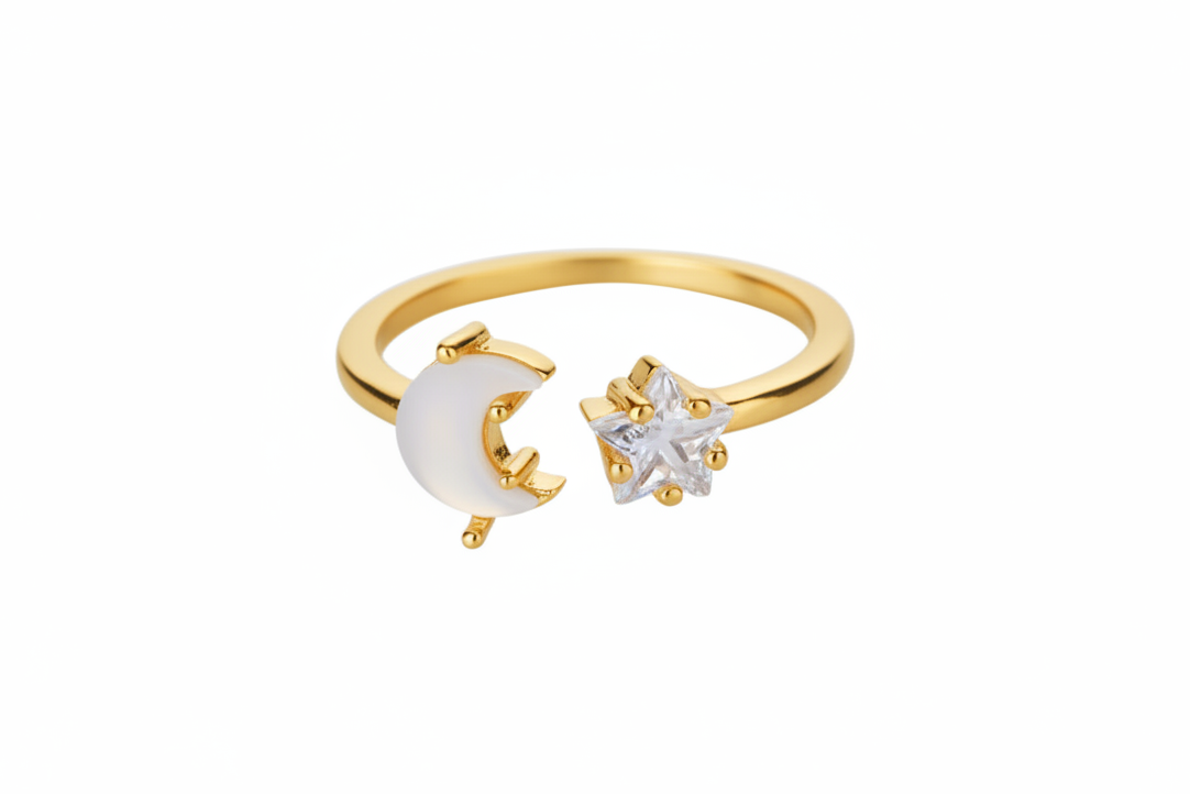 A toned gold open ring featuring a crescent moon moonstone and a small clear zircon star on the other side, shown on a plain white background.